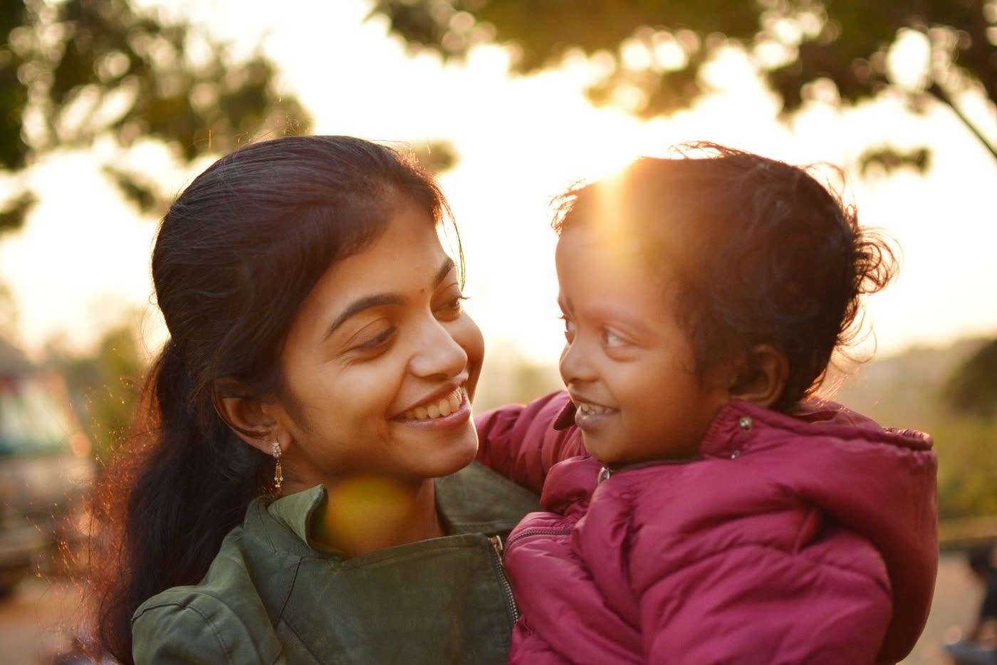 A young mother smiling with her little daughter in warm evening light