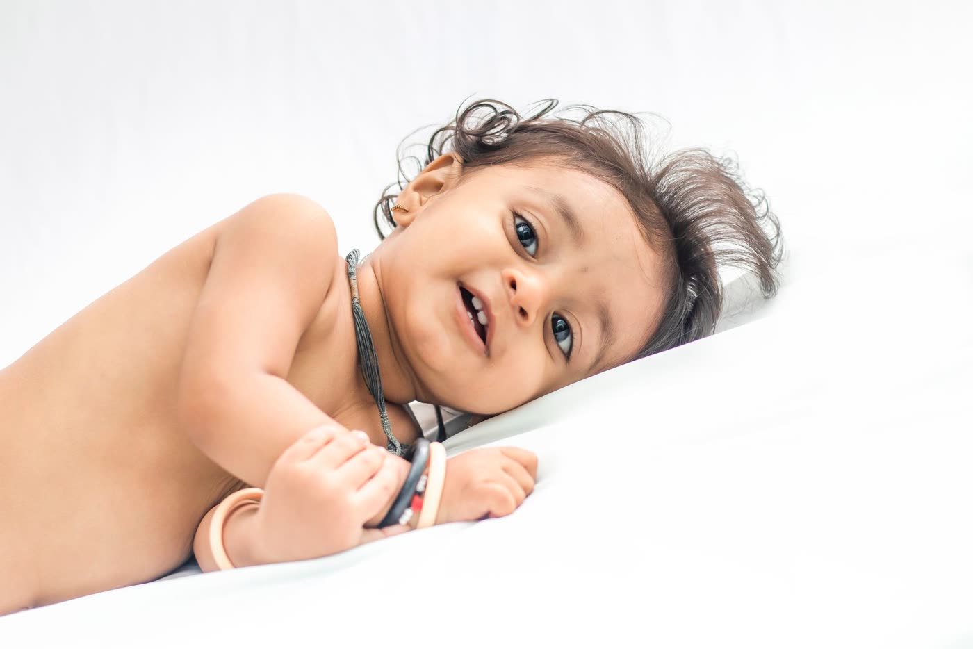 A smiling baby lying on a white bed