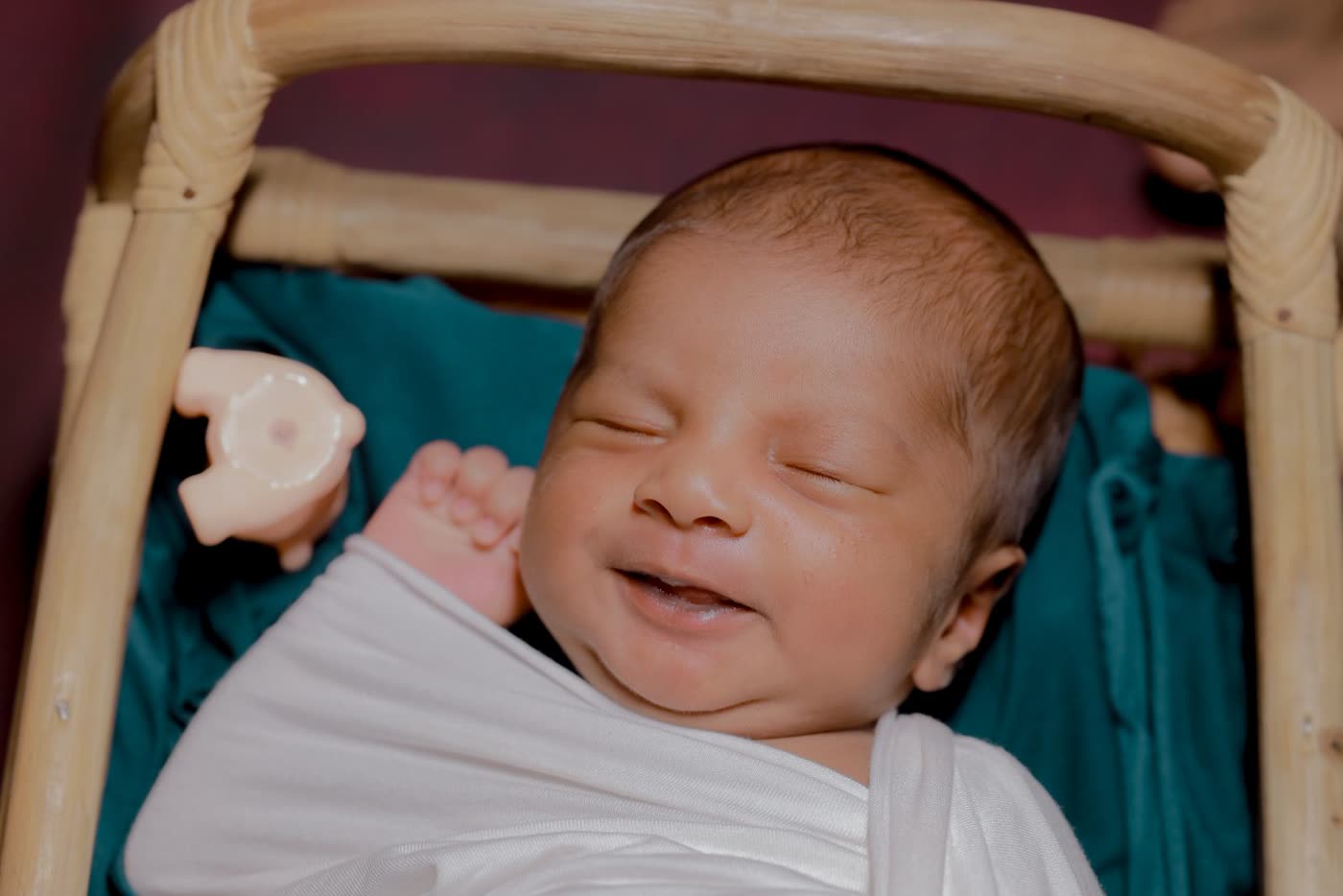 A newborn baby smiling in his sleep, wrapped in a white cloth